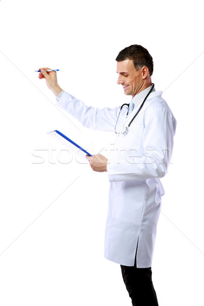 Man doctor writing with pen at copyspace and holding clipboard over white background Stock photo © deandrobot