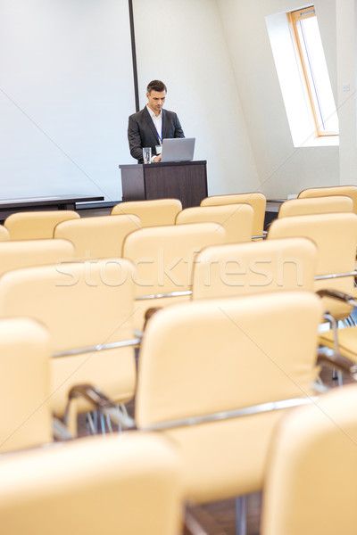 Pensive businessman standing and using laptop in empty meeting hall Stock photo © deandrobot
