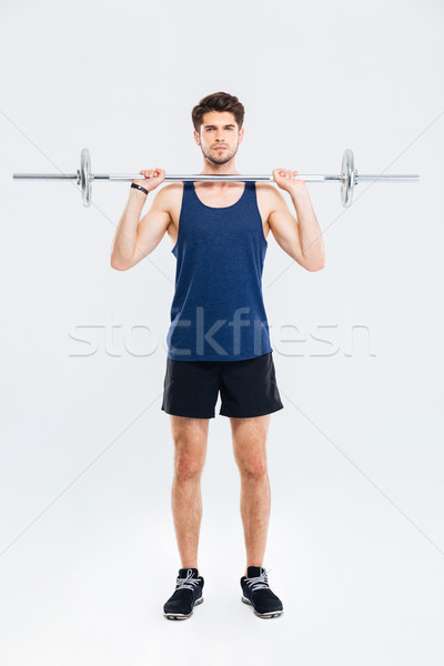 Stock photo: Full length of concentrated man athlete working out with barbell