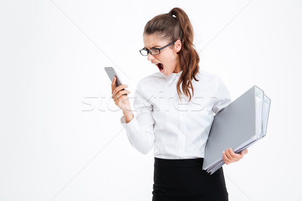 Angry mad businesswoman in glasses using cell phone and shouting Stock photo © deandrobot