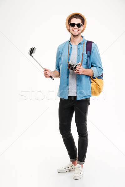 Cheerful young tourist, old camera and smartphone on selfie stick Stock photo © deandrobot