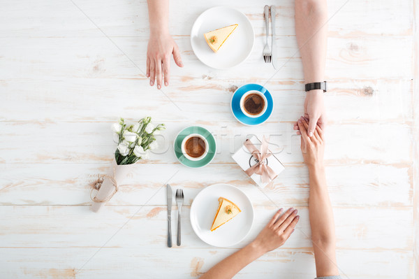 Top view of couple eating dessert and holding hands Stock photo © deandrobot