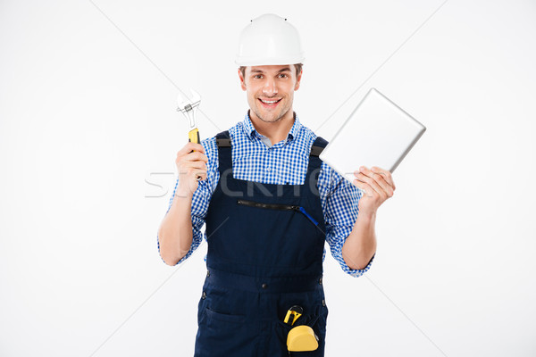 Happy male builder showing thumb up and holding pc tablet Stock photo © deandrobot