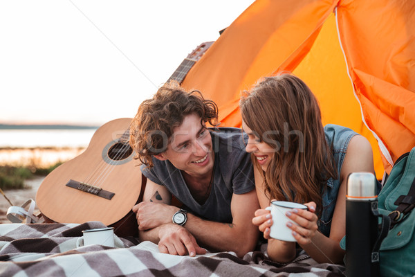 Happy young couple lying and drinking tea in touristic tent Stock photo © deandrobot