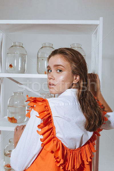 Woman taking jar with gold fish from the closet Stock photo © deandrobot