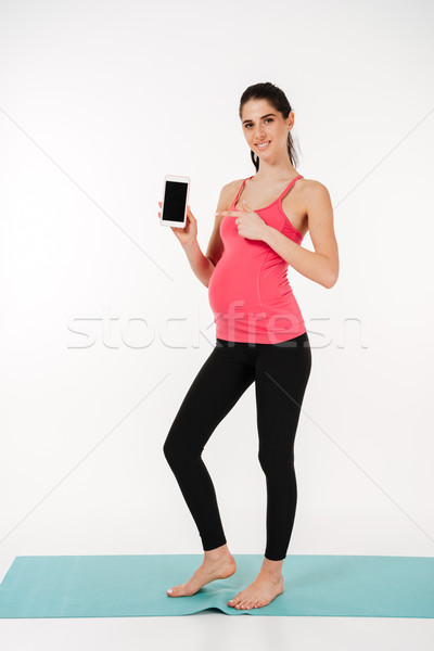 Full length portrait of a smiling healthy pregnant woman Stock photo © deandrobot