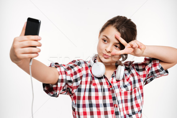 Happy young girl wearing headphones make a selfie Stock photo © deandrobot