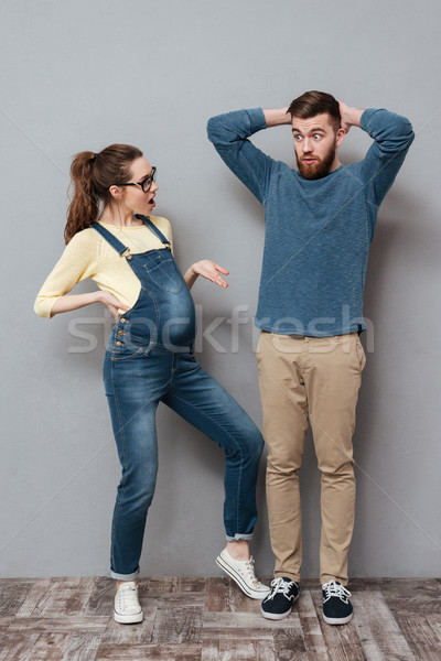 Pregnant serious woman looking at confused man. Stock photo © deandrobot