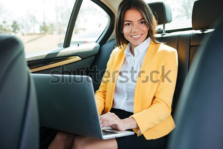Businesswoman sitting on back seat of car and working Stock photo © deandrobot