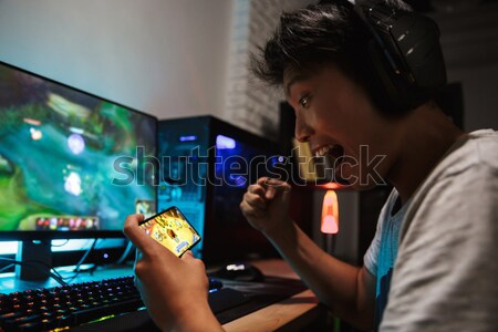 Young man sitting at home indoors. Focus on remote control. Stock photo © deandrobot