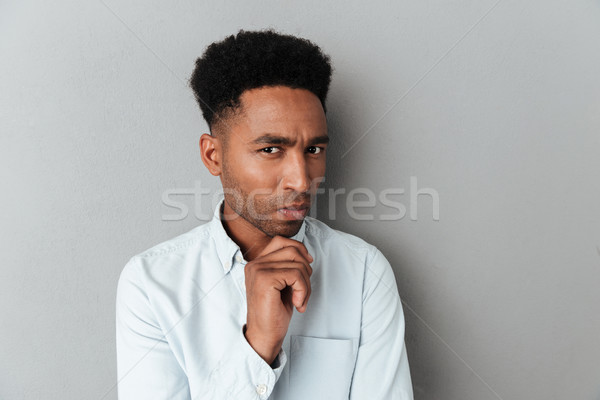 Young pensive african man looking closely at camera Stock photo © deandrobot