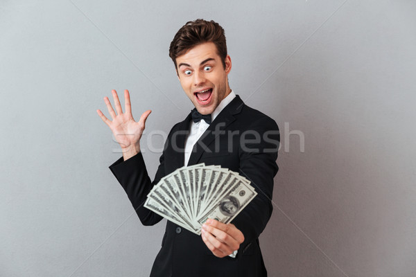 Excited screaming man in official suit holding money. Stock photo © deandrobot