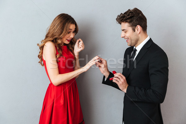 Portrait of a cheerful man putting on an engagement ring Stock photo © deandrobot