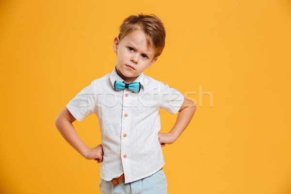 Angry little boy child standing isolated over yellow Stock photo © deandrobot