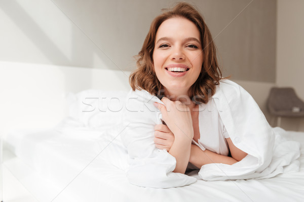 Cheerful lady lies on bed indoors home Stock photo © deandrobot