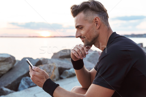 Portrait of a smiling sportsman using mobile phone Stock photo © deandrobot