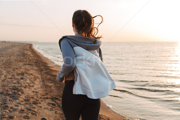Back view of young sportswoman running at the beach Stock photo © deandrobot