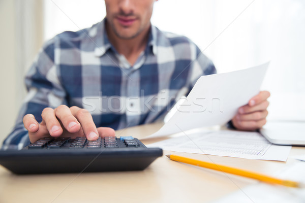 Man with calculator checking bills Stock photo © deandrobot