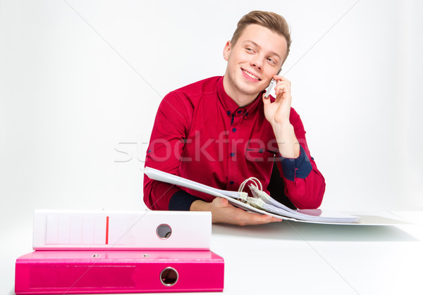 Playful cheerful young man using binders and talking on cellphone Stock photo © deandrobot
