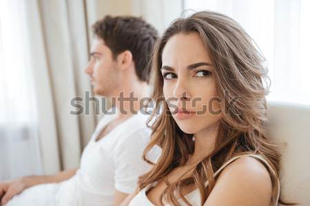 Unhappy woman in bed with man on the back Stock photo © deandrobot