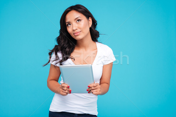 Pensive woman holding tablet computer and looking up Stock photo © deandrobot