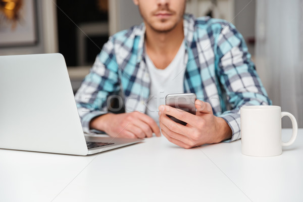 Fotografia człowiek telefonu komórkowego laptop młody człowiek shirt Zdjęcia stock © deandrobot