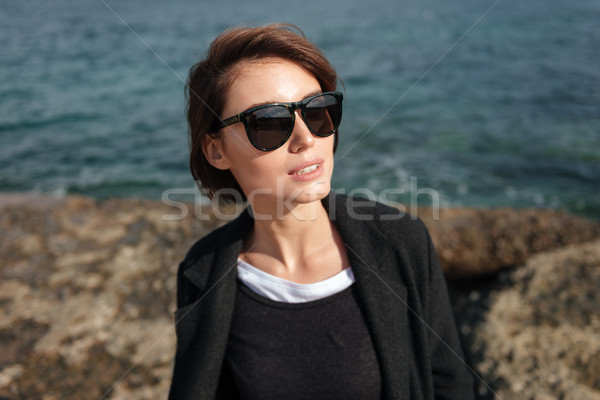 Stylish woman in sunglasses standing near the sea Stock photo © deandrobot