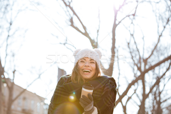 Cheerful woman drinking coffee and laughing outdoors in autumn Stock photo © deandrobot