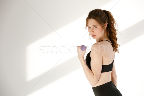 Serious pretty young sports lady posing with dumbbell Stock photo © deandrobot
