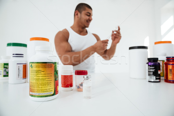 Sportsman standing over white background holding syringle Stock photo © deandrobot