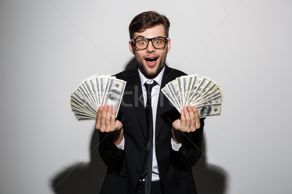 Happy exited man in glasses and black suit holding two bunches o Stock photo © deandrobot