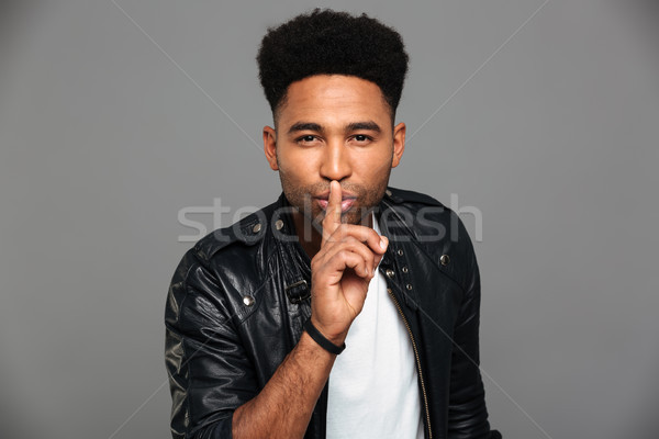 Handsome african guy with stylish haircut showing silence gestur Stock photo © deandrobot