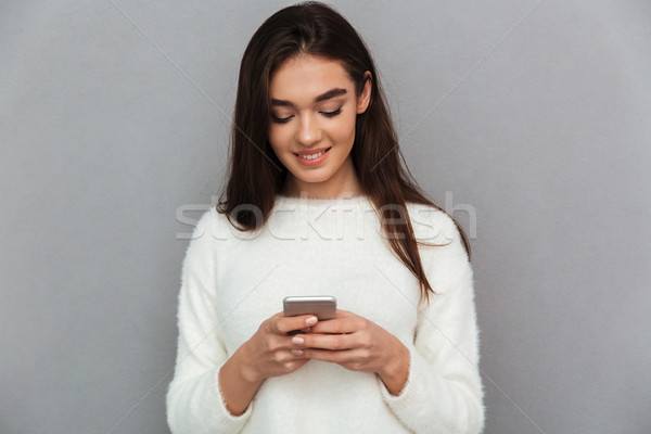 Young smiling brunette woman in white pullover checking news on  Stock photo © deandrobot