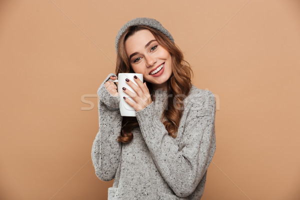 Cheerful brunette woman in warm clothes warming while holding cu Stock photo © deandrobot