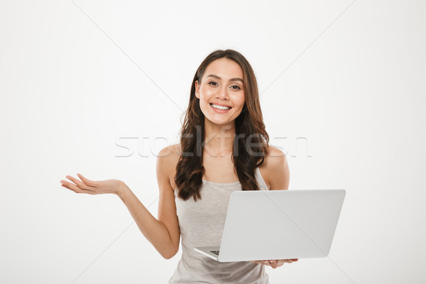 Image of amazing businesswoman holding silver laptop and gesturi Stock photo © deandrobot