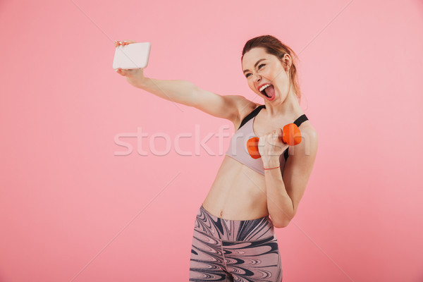 Screaming playful sportswoman making selfie on smartphone while doing exercise Stock photo © deandrobot