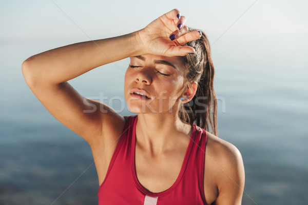 Tired sportswoman wiping her forehead after jogging Stock photo © deandrobot