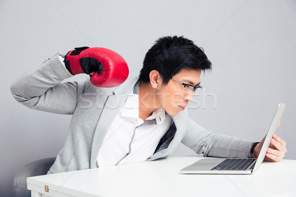 Businessman in boxing gloves reading to hit laptop  Stock photo © deandrobot