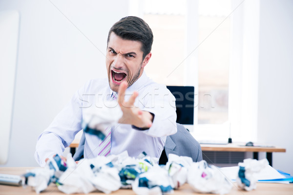Angry businessman throwing crumpled paper on camera Stock photo © deandrobot