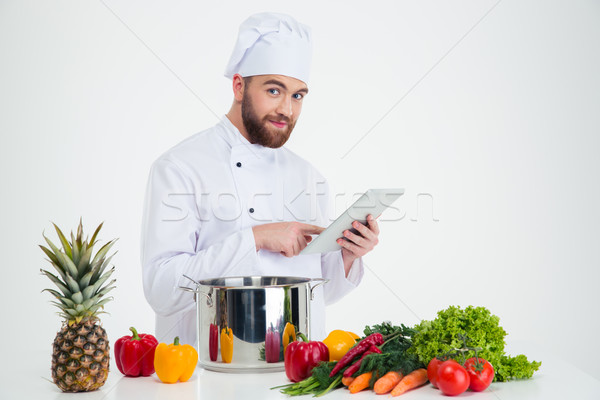 Stock photo: Male chef cook using tablet computer while preparing foo
