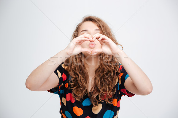 Woman showing heart gesture with fingers Stock photo © deandrobot