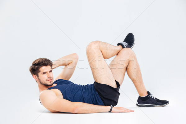 Serious young man athlete exercising and doing crunches Stock photo © deandrobot