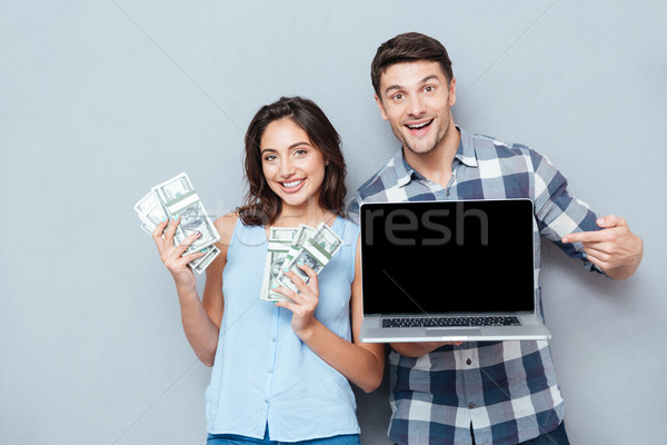 Portrait of happy young couple using laptop over gray background Stock photo © deandrobot