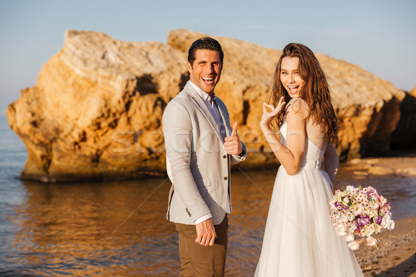 Just-married couple walking at beach and showing ok sign Stock photo © deandrobot