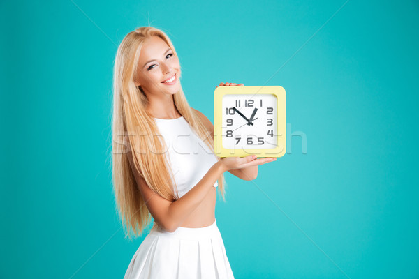 Smiling cheerful girl with long hair holding wall clock Stock photo © deandrobot