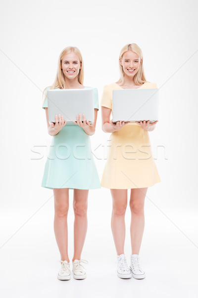 Two ladies looking at the camera and holding laptops Stock photo © deandrobot