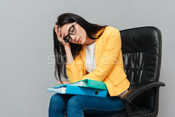 Tired woman holding folders while sitting on office chair Stock photo © deandrobot