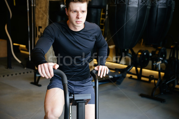 Stock photo: Serious Athletic man using spinning bicycle