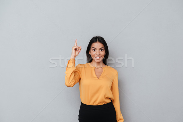 Stock photo: Portrait of a smiling happy businesswoman pointing finger up