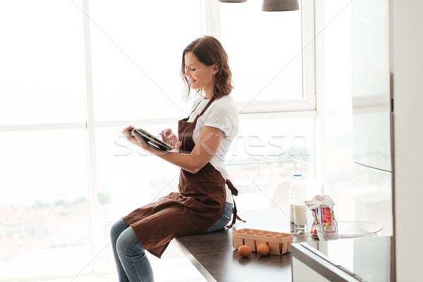 Yandan görünüş gündelik kadın önlük oturma tablo Stok fotoğraf © deandrobot